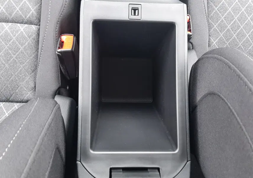 Vue plongeante sur le rangement central noir entre les sièges tissu gris à motifs du MG Motor ZS 1.5 Hybrid+ 2026.