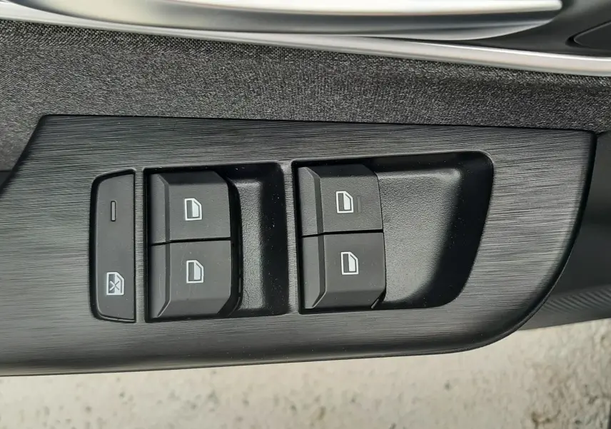 Gros plan sur les commandes de lève-vitres noires sur la porte intérieure du MG Motor ZS Camden Grey 2026.