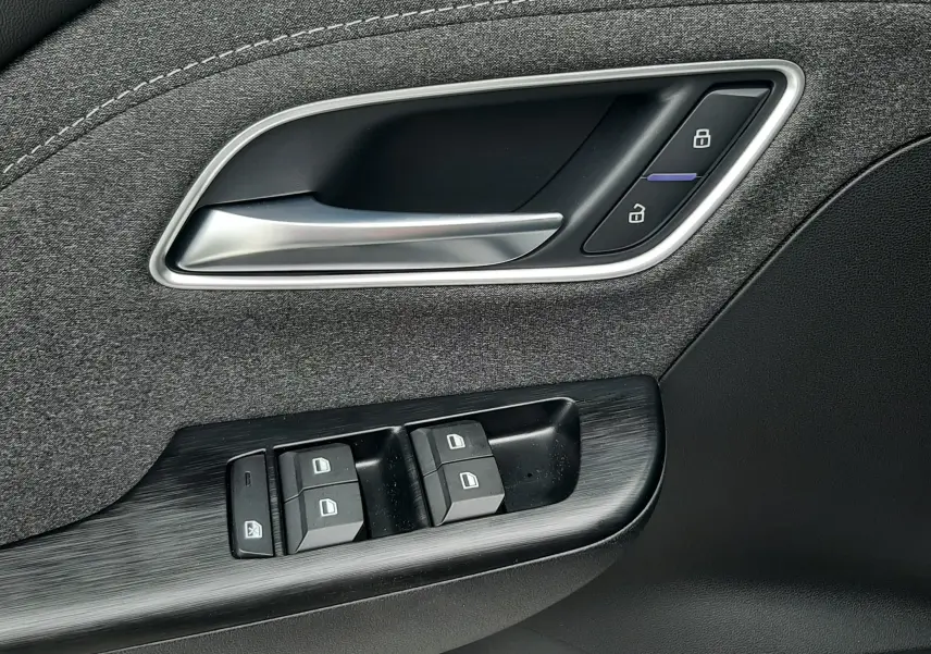 Gros plan sur la poignée intérieure et les commandes de porte côté conducteur du MG ZS 1.5 HYBRID+ 2026 en Camden Grey.