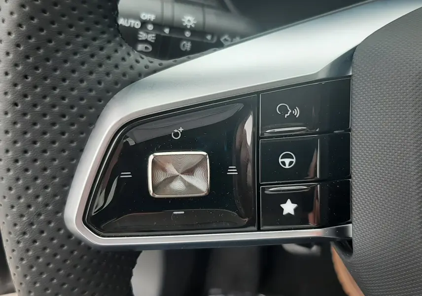 Gros plan sur les commandes gauche du volant perforé du MG Motor ZS Camden Grey 2026 hybride avec boutons multifonctions.