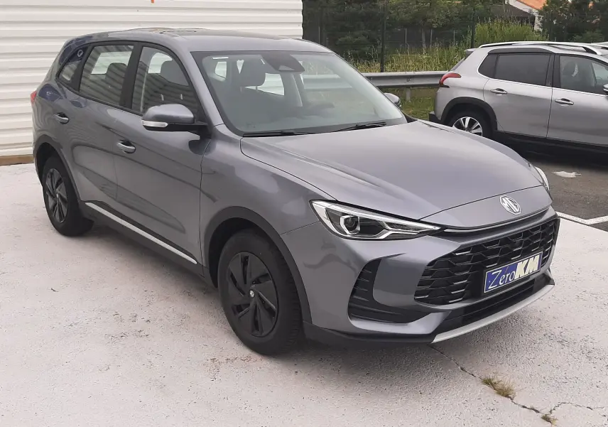 Vue 3/4 avant gauche du MG ZS Camden Grey 2026 hybride essence avec calandre noire et jantes foncées.