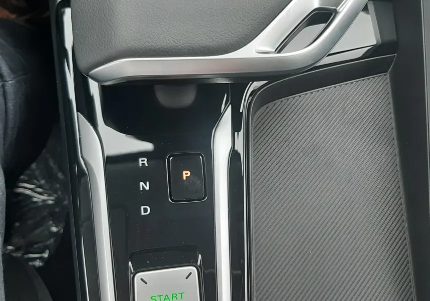 Vue rapprochée de la console centrale noire brillante du MG ZS 1.5 Hybrid+ 2026 avec sélecteur de vitesses et bouton Start Stop.