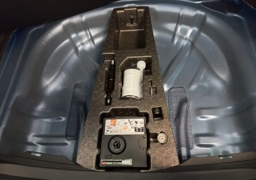Vue rapprochée du coffre d’une SEAT LEON Bleu Saphir 2025 montrant le rangement pour kit de réparation pneus.