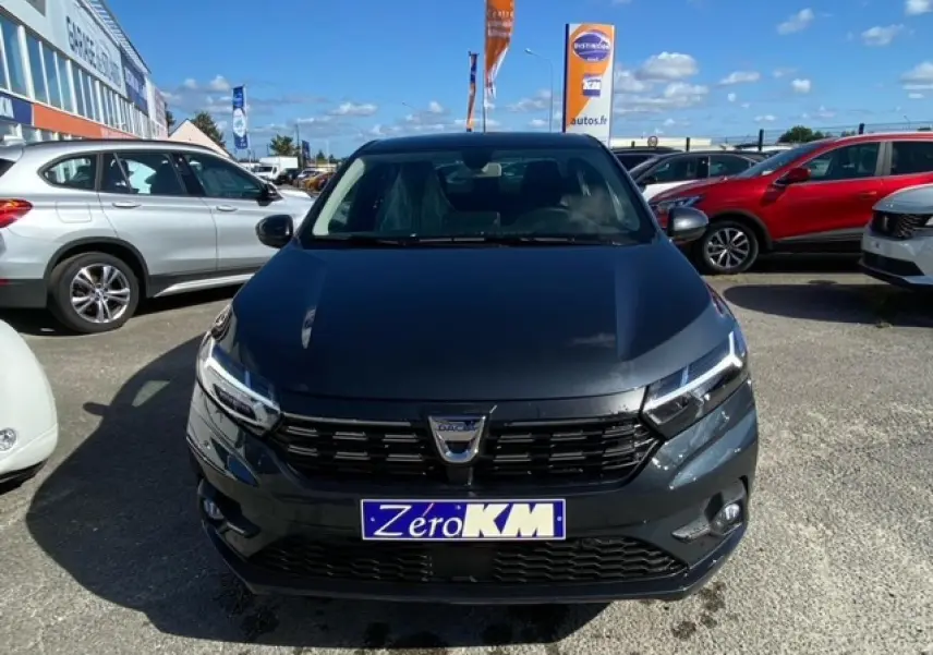 Vue avant d'une Dacia Logan gris foncé 2022 avec calandre noire et plaque "Zero KM" en concession.