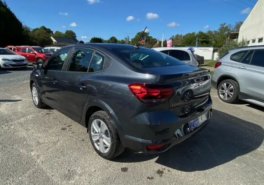 Vue 3/4 arrière droite d'une Dacia Logan gris métallisé 2022 avec feux arrière LED et caméra de recul visible.