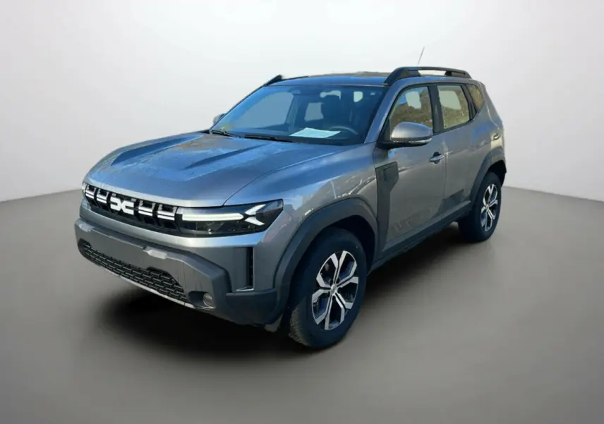 SUV Dacia Duster 2025 gris schiste en 3/4 avant droit avec calandre distinctive et barres de toit noires.