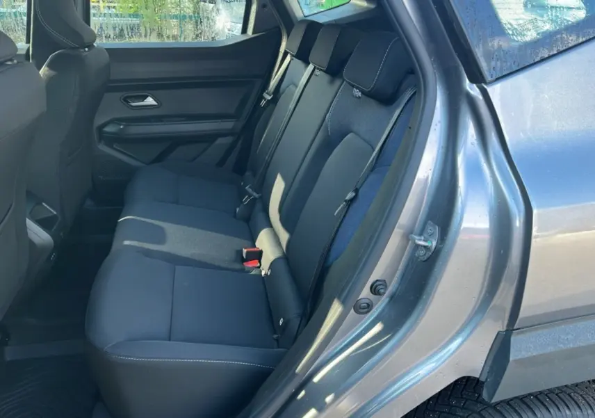 Vue côté droit sur l'intérieur arrière du Dacia Duster 2025 gris schiste, montrant les sièges arrière en tissu noir.