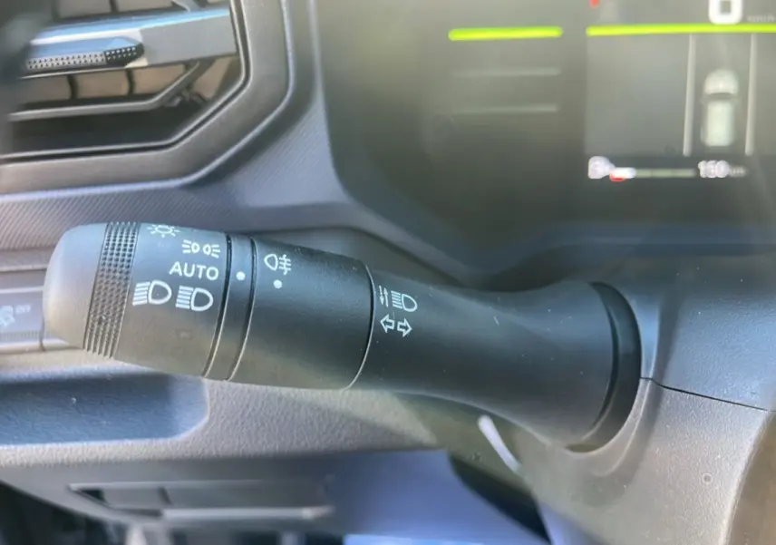 Le levier de commande des phares et clignotants du Dacia Duster 2025 gris schiste, vue intérieure côté gauche.