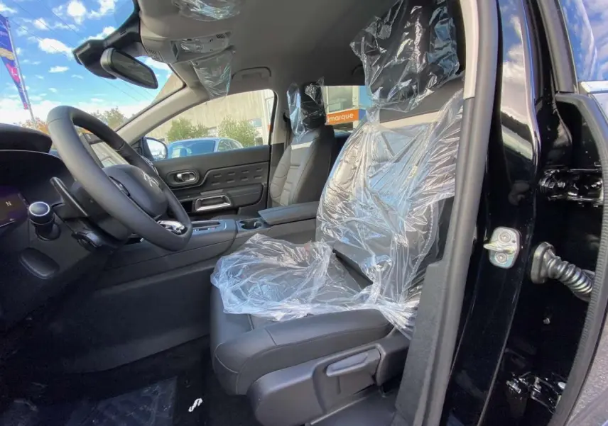 Intérieur côté conducteur du Citroën C5 Aircross noir perla 2025, sièges avant protégés par film plastique.