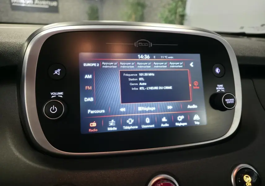 Écran tactile multimédia de la Fiat 500X rouge 2024 affichant la radio RTL avec commandes autour en tableau de bord noir.