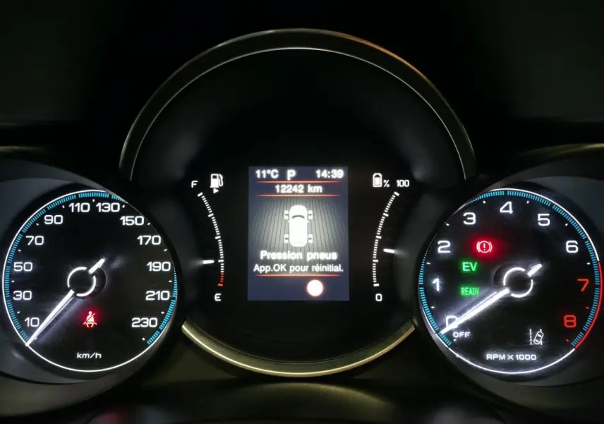 Tableau de bord de Fiat 500X rouge 2024 montrant l'affichage de pression pneus et compteurs vitesse et tours moteur.