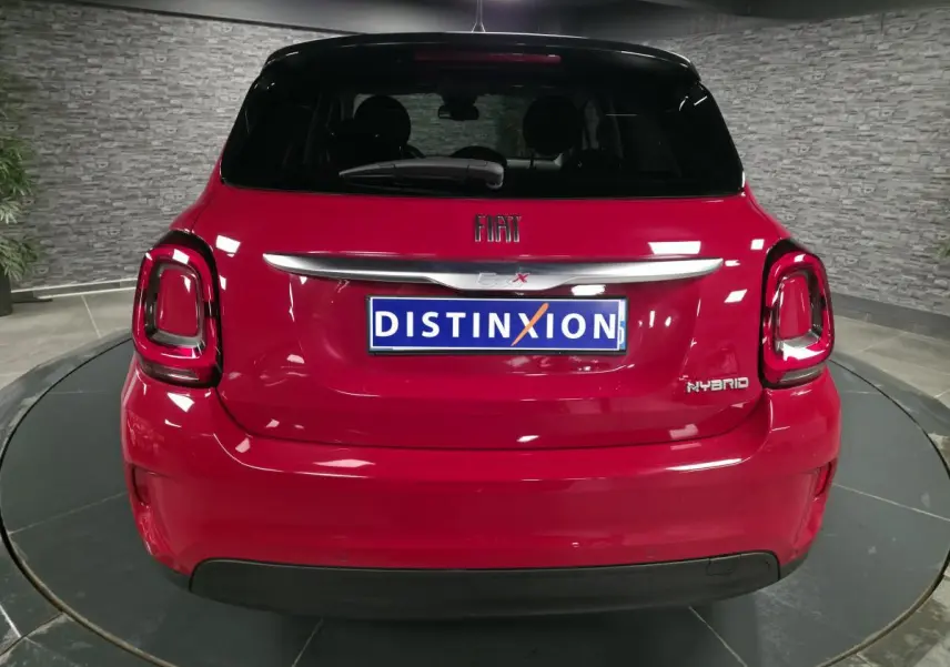 Vue arrière d'un Fiat 500X rouge Passion avec logo FIAT et badge Hybrid sur fond intérieur gris.
