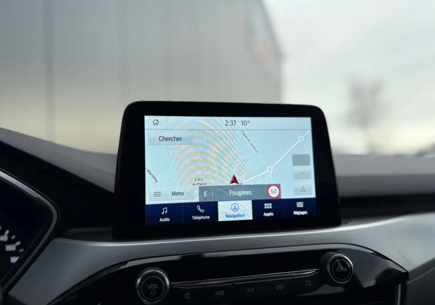 Écran tactile GPS du Ford Kuga 2024 affichant la navigation, vu de face dans l'habitacle noir.