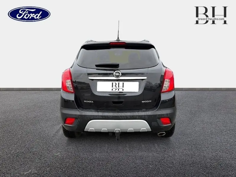 Vue arrière d'un Opel Mokka noir carbone avec attelage et feux rouges visibles sur fond neutre.
