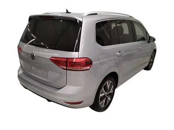 Vue 3/4 arrière droite d’un Volkswagen Touran gris 2025 avec vitres surteintées et jantes alliage.