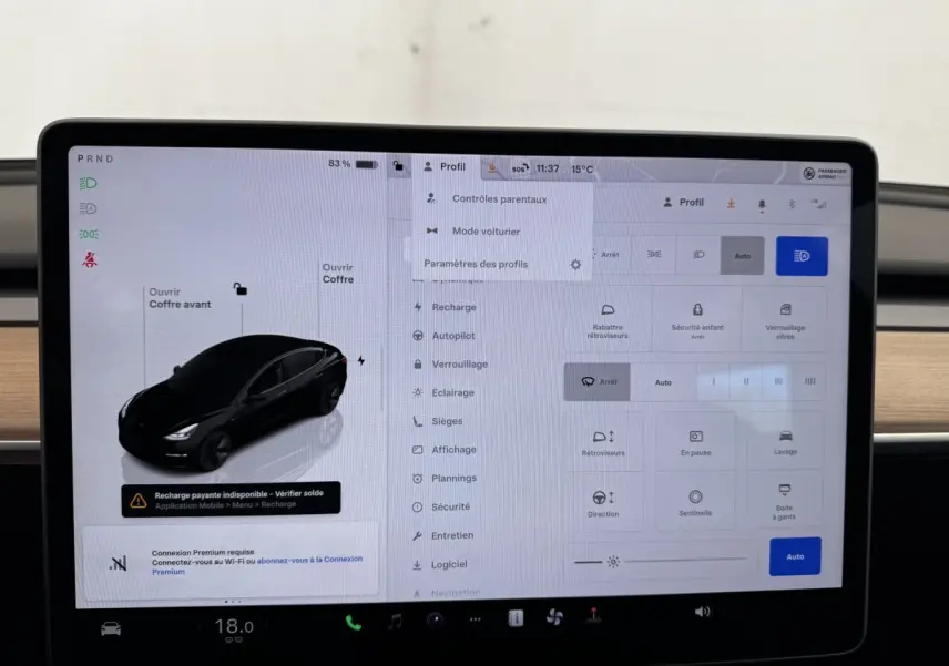 Écran tactile central affichant les réglages d’une Tesla Model 3 noire, vue de profil sur l’interface du véhicule.