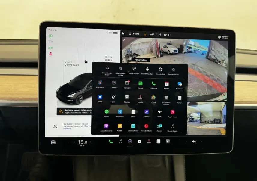 Écran tactile central de la Tesla Model 3 noir 2023 affichant la caméra de recul et le menu multimédia.
