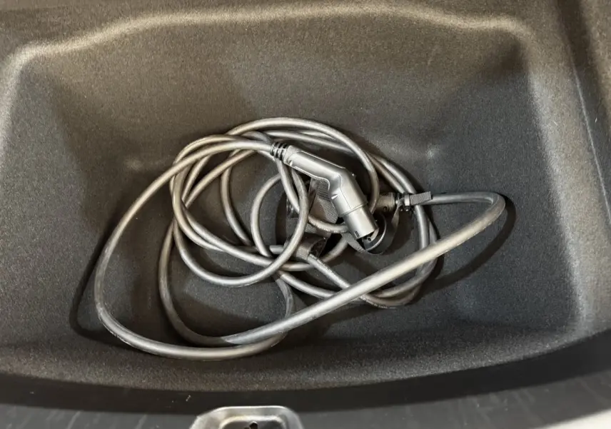 Câble de recharge électrique noir dans le coffre avant d'une Tesla Model 3 Grande Autonomie 2023.