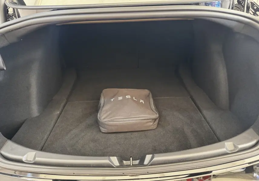 Coffre ouvert d'une Tesla Model 3 noire 2023, avec sac de charge Tesla au centre, vue arrière.