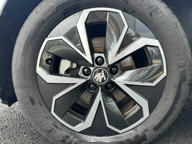 Gros plan sur la jante alu noire et argentée avec logo ŠKODA au centre d’un pneu Goodyear sur ŠKODA SCALA blanc cristal.
