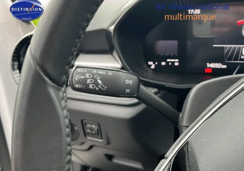 Gros plan sur la commande multifonction noire à gauche du volant cuir d'une Skoda Fabia blanche, tableau de bord numérique visible.