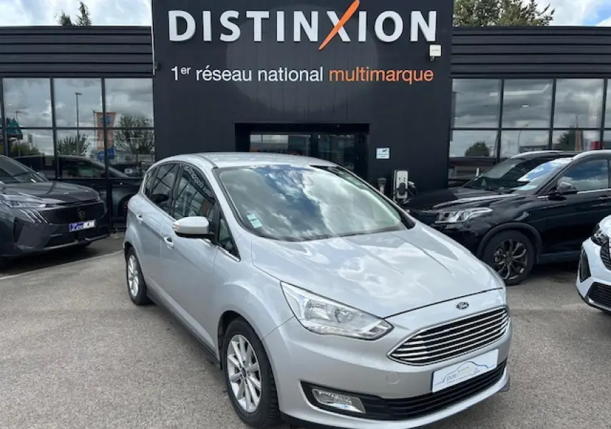 Ford C-MAX II gris clair métal en 3/4 avant droit, avec calandre chromée et jantes alliage 16 pouces visibles.