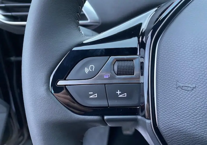 Gros plan sur les commandes vocales et volume au volant noir du Peugeot 5008 2023 essence finition Active Pack.