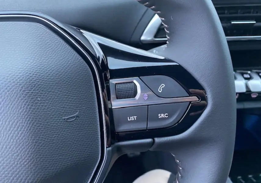 Gros plan sur les commandes du volant côté gauche du Peugeot 5008 noir, avec boutons de téléphone et menu.