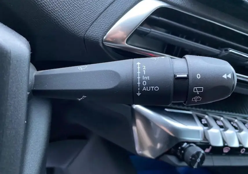 Gros plan sur la commande d'essuie-glace du Peugeot 5008 2023 avec tableau de bord noir et détails argentés.