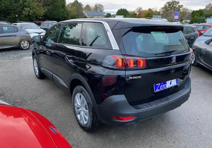 Peugeot 5008 noir vue 3/4 arrière droit avec feux arrière LED et jantes alliage 16 pouces sur parking extérieur.