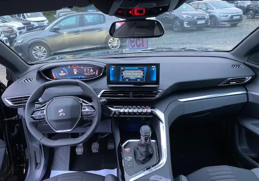Vue intérieure avant du Peugeot 5008 noir 2023, tableau de bord moderne avec écran tactile et volant compact multifonction.