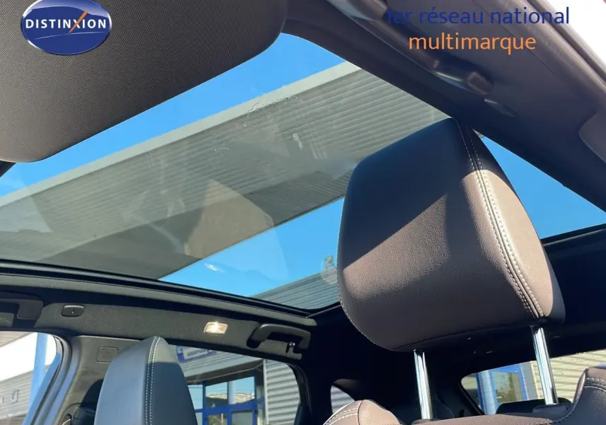 Vue intérieure sur les sièges avant en cuir noir et le toit panoramique du Nissan Qashqai blanc nacré 2025.