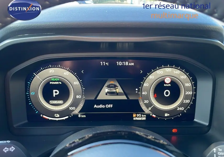 Tableau de bord numérique du Nissan Qashqai 2025 affichant la vitesse, la puissance et l'autonomie, vue de face depuis le poste de conduite.