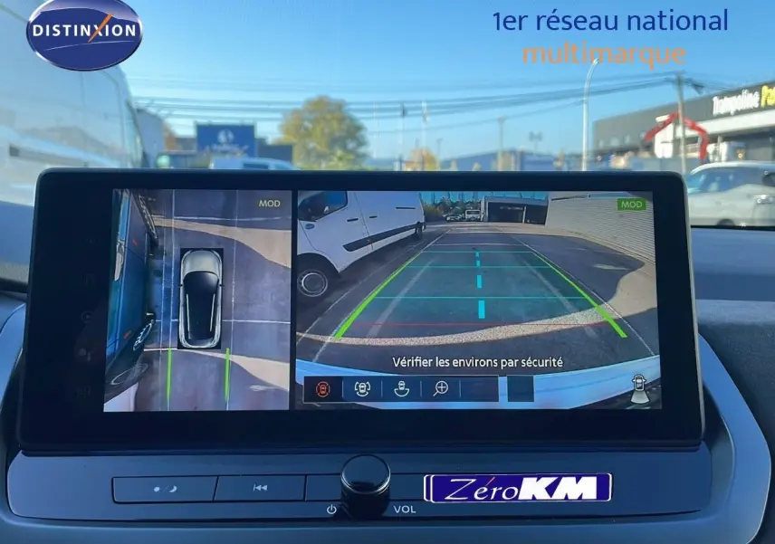 Écran multimédia du Nissan Qashqai blanc nacré, affichant la caméra de recul avec vue arrière et vue aérienne du parking.