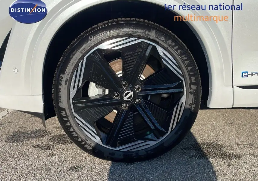 Gros plan sur la roue avant droite du Nissan Qashqai blanc nacré avec jante noire et détails argentés.