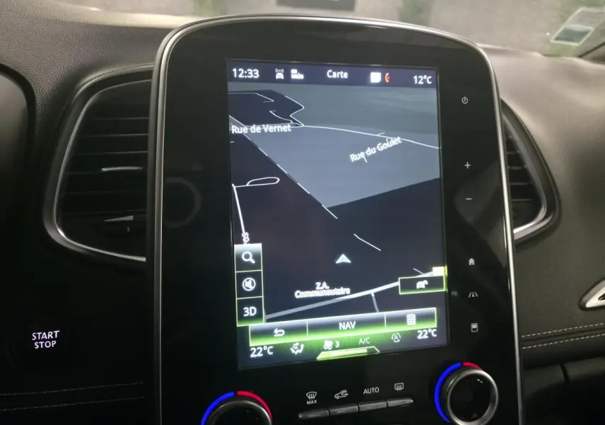Écran tactile central du Renault Scenic 2018 affichant la navigation, entouré de commandes de climatisation et bouton Start/Stop.