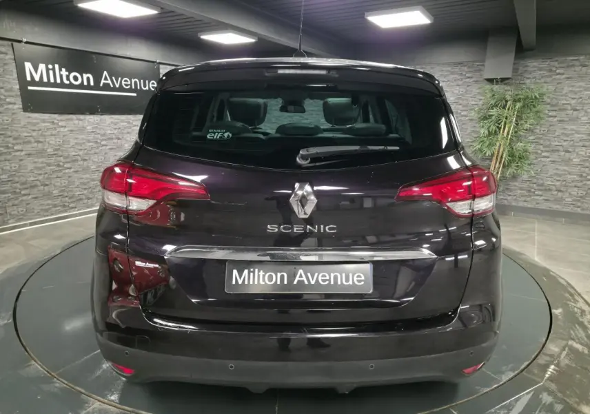 Vue arrière d'un Renault Scénic noir avec logo et nom du modèle visibles, dans un showroom intérieur.