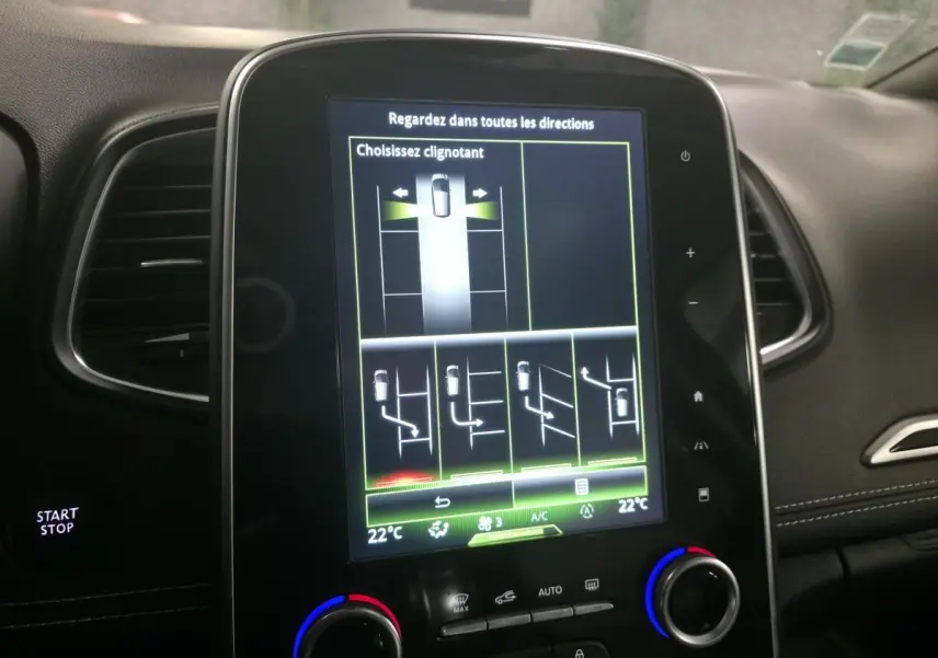 Écran tactile central du tableau de bord du Renault Scénic noir, affichant l'aide au stationnement avec choix de clignotant.