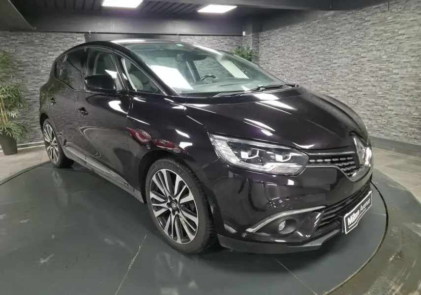 Renault Scénic noir améthyste en 3/4 avant droit, avec jantes alliage et calandre chromée Starlight visible.