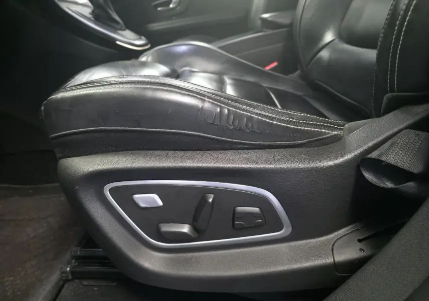 Gros plan sur le siège conducteur en cuir noir avec commandes électriques sur le côté d'un Renault Scenic IV Initiale Paris.