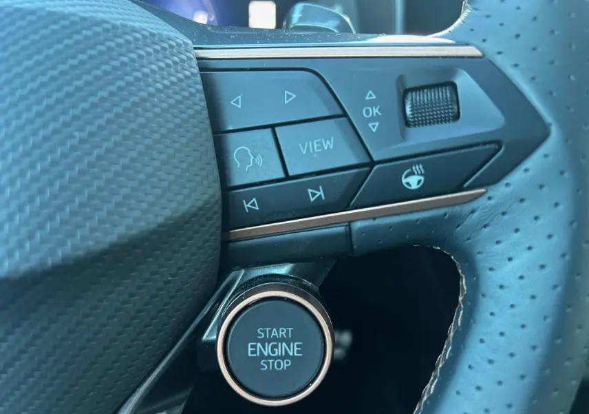 Gros plan sur les commandes et le bouton start/stop du volant perforé en cuir noir du CUPRA Formentor blanc neige.