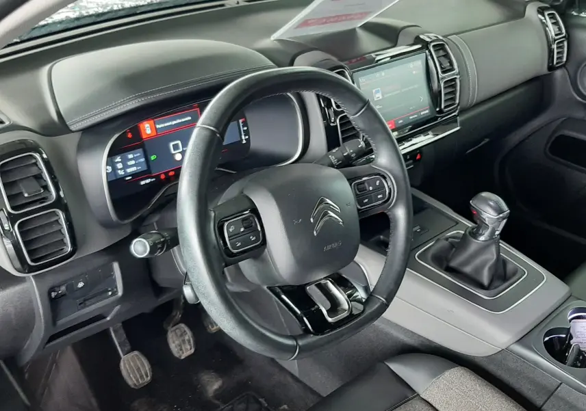 Vue intérieure du poste de conduite du Citroën C5 Aircross 1.2 PureTech 2021, volant cuir, boîte manuelle et écran tactile.