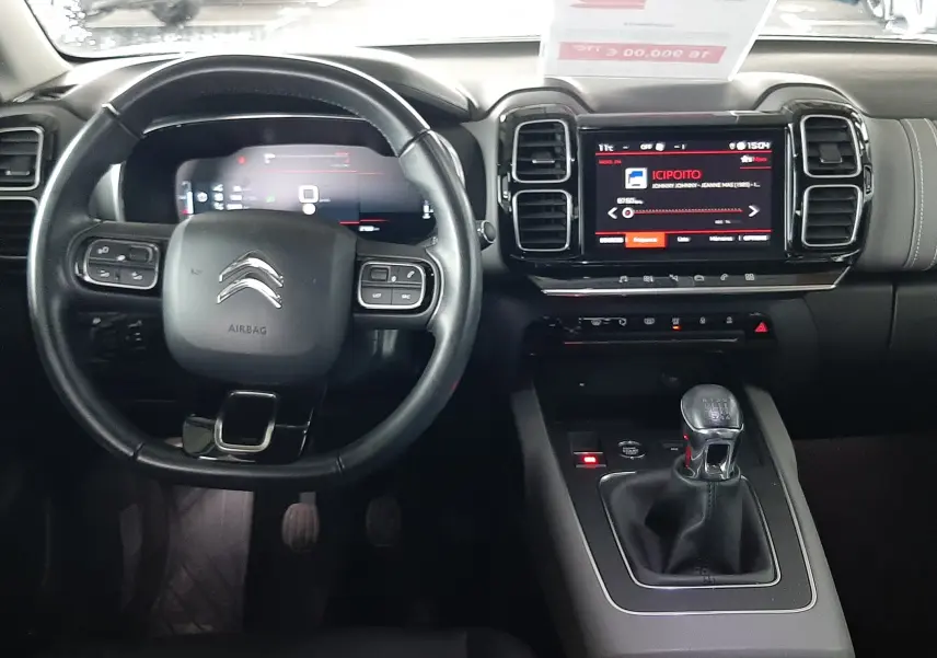 Vue intérieure frontale du tableau de bord et volant du Citroën C5 Aircross gris avec boîte manuelle et écran tactile central.