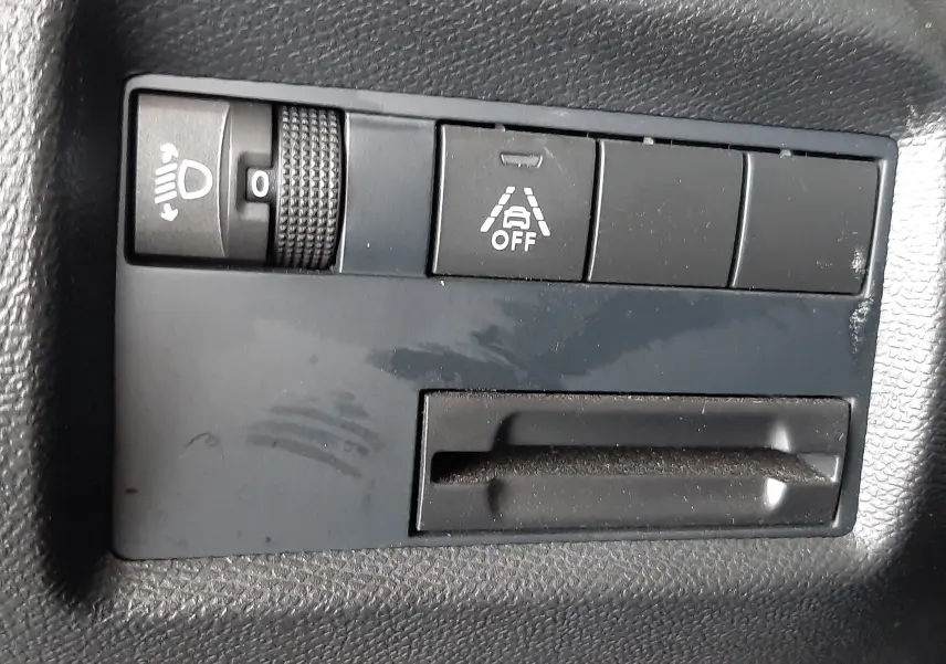 Gros plan sur les commandes de réglage des phares et d'activation de l'alerte de franchissement de ligne dans une Citroën C5 Aircross gris Artense.