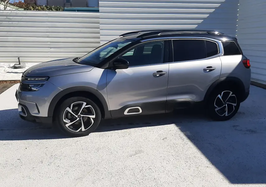 Citroën C5 Aircross gris Artense avec toit noir, vue de profil côté gauche, jantes bi-ton et protections latérales noires.