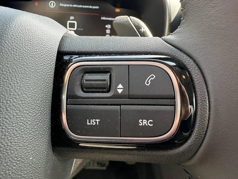 Gros plan sur les commandes multifonctions noires du volant côté gauche du Citroën C5 Aircross 2025, finition Gris Platinium.