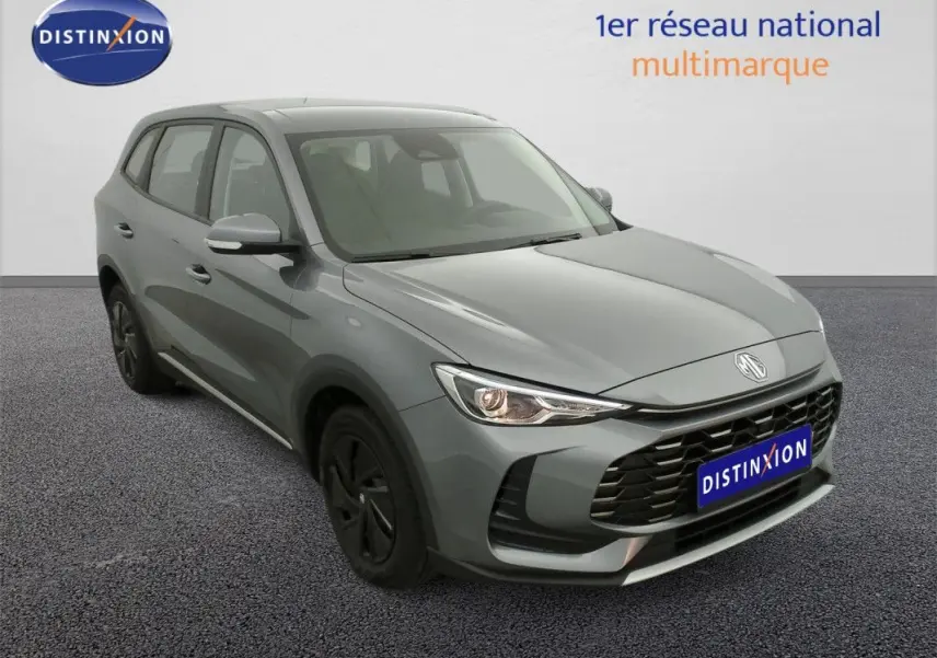 Vue 3/4 avant d’un MG ZS 1.5L hybride gris Hampstead avec calandre noire et jantes foncées.