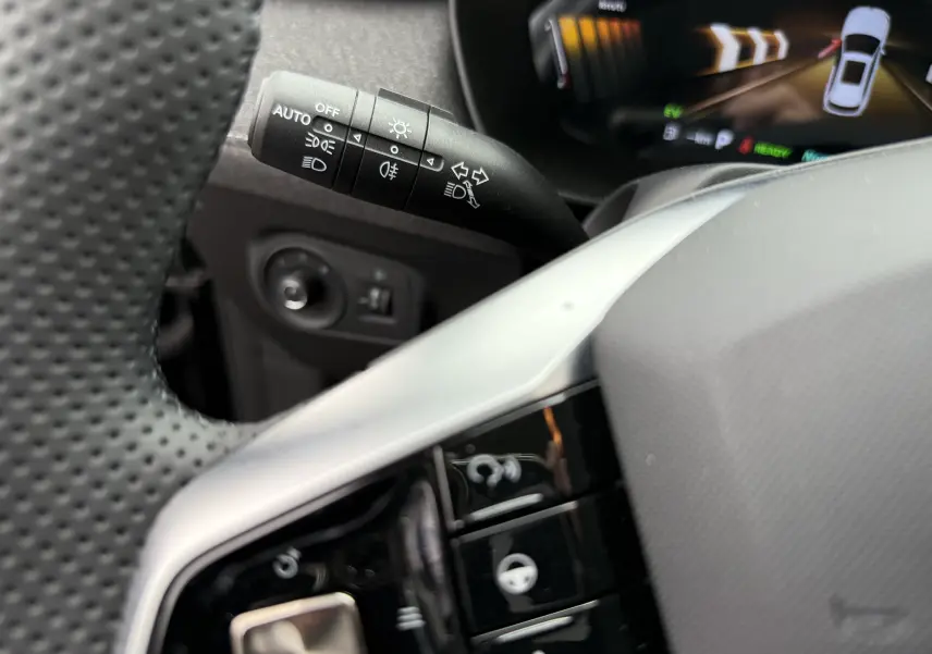 Gros plan sur la manette de clignotants et les commandes au volant du MG ZS 1.5L Hybrid+ 2026, intérieur noir.