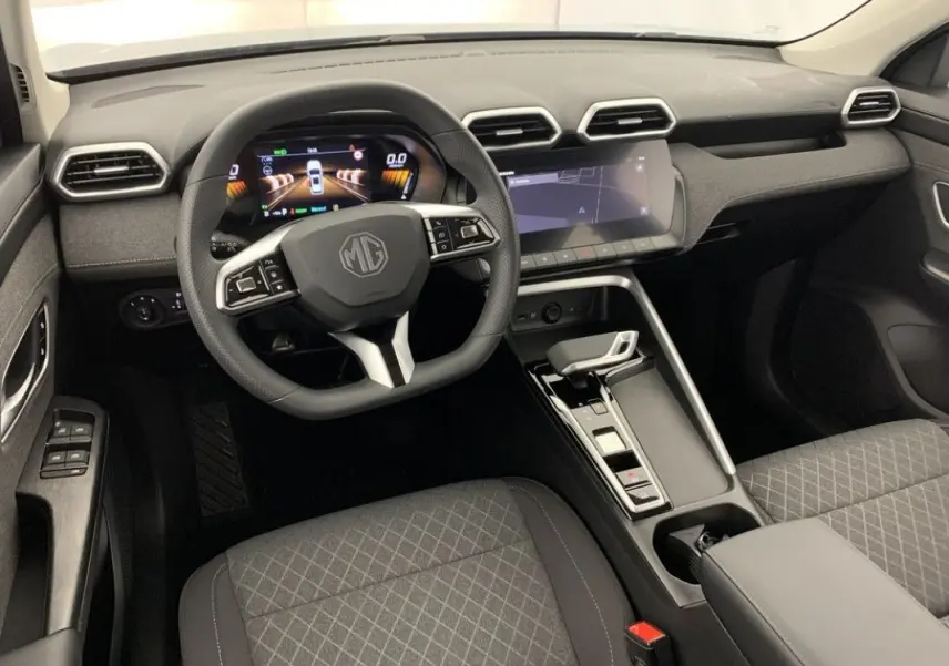 Vue intérieure de face du poste de conduite du MG ZS 1.5L Hybrid+ 2026 en tissu gris avec tableau de bord numérique et écran tactile.