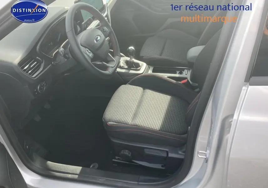 Intérieur avant droit de la Ford Focus gris 2025, volant trois branches avec coutures rouges et boîte manuelle visible.